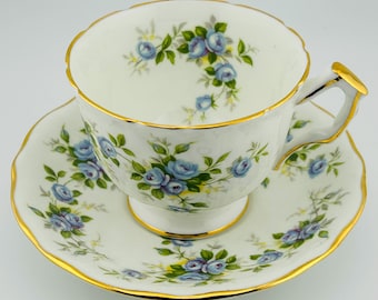 Può includere: Un set da tè bianco con un motivo floreale blu e verde. Il set ha un bordo dorato.