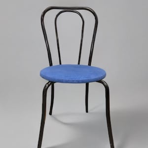 May include: A black metal chair with a blue upholstered seat. The chair has a simple design with a curved back and four legs.