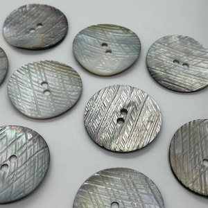 May include: Eight round, iridescent, mother-of-pearl buttons with a textured, criss-cross pattern. Each button has two holes.