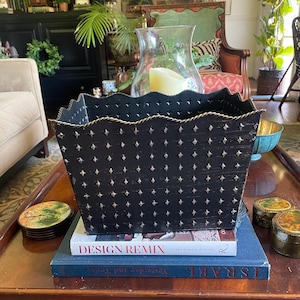 May include: A rectangular black metal container with a scalloped top edge and a repeating pattern of small, embossed star shapes. The rim features a twisted gold-tone rope detail, and the black finish has a subtle, distressed texture.