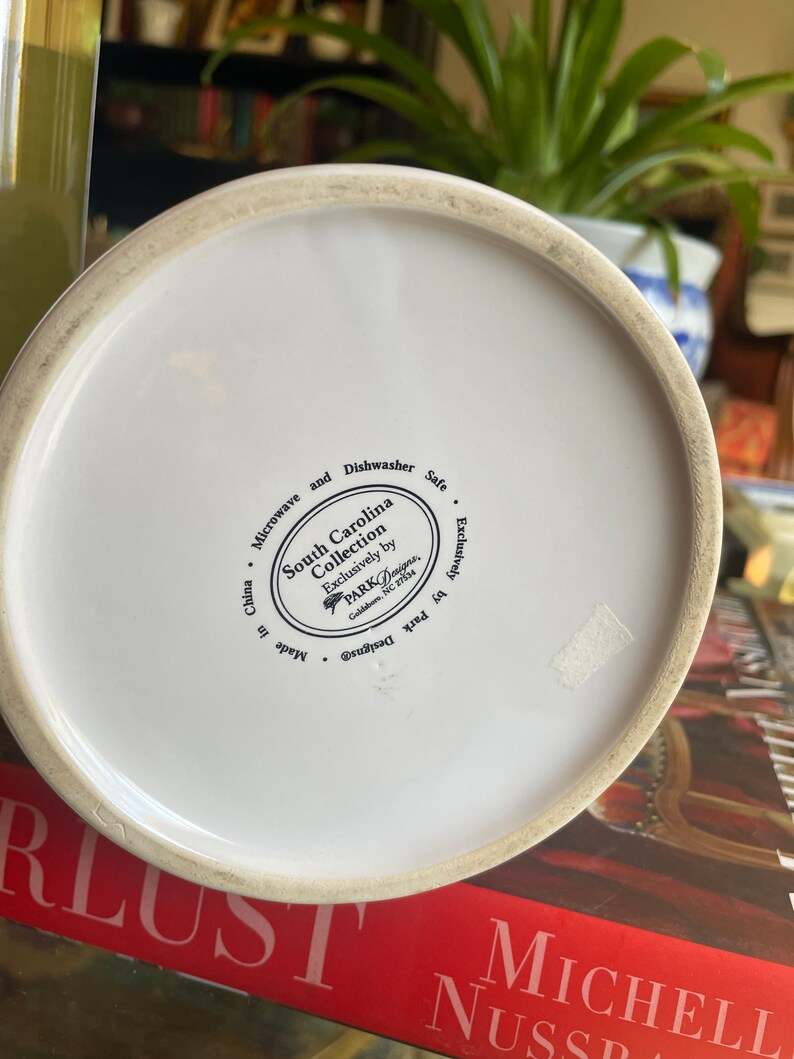 Może przedstawiać: Biały dzbanek ceramiczny z czarno-białym wzorem. Na spodzie dzbanka znajduje się etykieta z napisem "South Carolina Collection Exclusively by PARK Designs, Goldsboro, NC 27534. Made in China. Microwave and Dishwasher Safe. Exclusively by Park Designs."