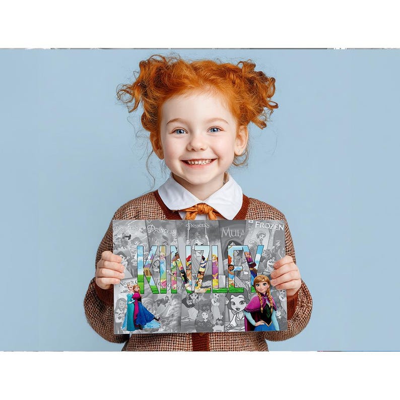 A young girl with curly red hair is smiling and holding up a sign with the name "KINLEY" written on it.