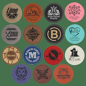 May include: A collection of 15 round leather coasters with various designs and text. The coasters feature a variety of colours, including brown, blue, red, white, black, and green. The text on the coasters includes "Lime", "Mountains Camping", "Heartland Hotels", "Yoga Leah's Yoga Studio", "Red Bird", "Compass Designs", "Holland", "Marc Tires", "World Fidelity Corporate Retreat", "Loveland Music Festival Coordinator", "Vet Clinic", "Purple Tiger", "Basketball", and "B".