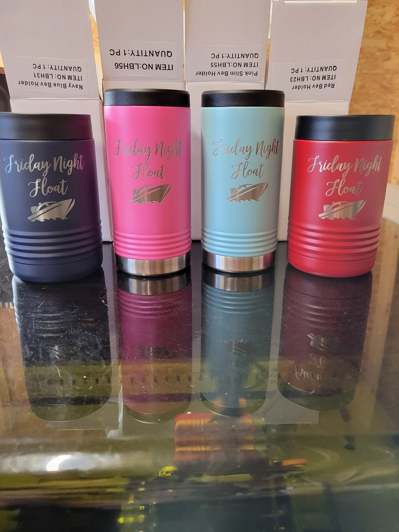 Peut inclure: Quatre porte-boissons isothermes avec une finition en acier inoxydable. Les porte-boissons sont en bleu marine, rose, turquoise et rouge. Chaque porte-boissons porte le texte "Friday Night Float" avec un petit graphique de bateau.