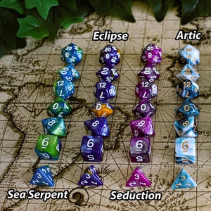 Pode incluir: Um conjunto de dez dados de sete faces em várias cores e padrões, incluindo azul, verde, roxo, vermelho e branco. Os dados estão dispostos em filas, com cada fila etiquetada com um nome diferente: Eclipse, Artic, Voidcaller, Sea Serpent, Seduction, Crimson e Ironclad.