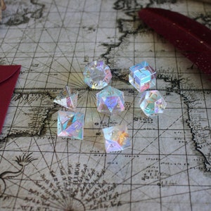 May include: A set of iridescent dice with gold numbers on a vintage map background. The dice are made of clear glass and have a rainbow effect.