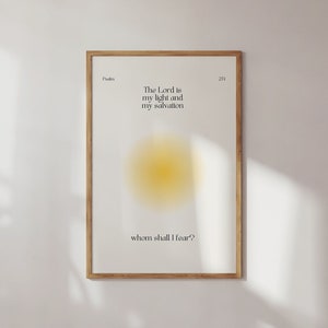 Puede incluir: Una impresión enmarcada con un marco de madera clara. La impresión presenta el texto "The Lord is my light and my salvation, whom shall I fear?" en una fuente minimalista, con un círculo degradado amarillo y blanco en el centro. La impresión se muestra en una pared blanca.