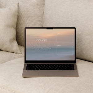Puede incluir: Un portátil que muestra un fondo de escritorio con el texto "Salmo 23" y dos cuadros etiquetados. El portátil está abierto y colocado sobre un sofá beige con una almohada a juego. La pantalla muestra un degradado de colores.