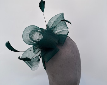 May include: A dark green hair accessory with a large bow made of netting and feathers.