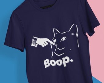 May include: Navy blue t-shirt featuring a white graphic of a cat being booped on the nose. The text "Boop." is printed below the cat.