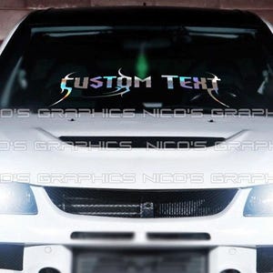 May include: A white car with a black roof. The windscreen features a holographic banner with the text "CUSTOM TEXT" in a stylized font. The car's headlights are illuminated. The banner has a tribal design.