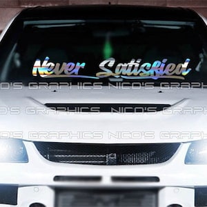 May include: A white car with a rainbow iridescent vinyl decal on the windshield that reads "Never Satisfied".