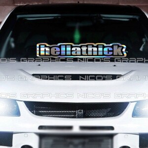 May include: A white car with a  "hellathick" sticker on the windshield. The sticker is iridescent and has a rainbow effect.