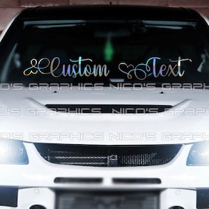 May include: A holographic car windshield decal with the words "Custom Text" in a script font. The decal is displayed on a white car. The brand name "Nico's Graphics" is printed at the bottom of the windshield.
