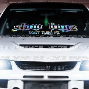 May include: A white car with a windshield decal that reads "Slow Boyz Don't Rush Me".