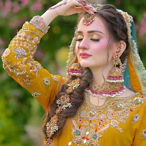 Peut inclure: Une femme portant une robe jaune brod&eacute;e avec des bijoux complexes en or et en perles. Elle porte une coiffure indienne traditionnelle avec un ornement de cheveux en or et un bindi sur le front.