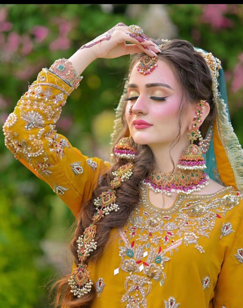 Peut inclure: Une femme portant une robe jaune brod&eacute;e avec des bijoux complexes en or et en perles. Elle porte une coiffure indienne traditionnelle avec un ornement de cheveux en or et un bindi sur le front.