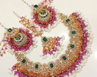 May include: A gold necklace set with green and white stones, pink, orange, and white beads, and pearl accents.