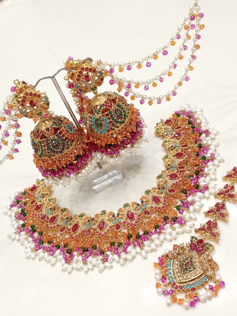 Peut inclure: Un collier en or avec un motif floral multicolore, rehauss&eacute; de perles et de perles color&eacute;es. Des boucles d'oreilles assorties avec un design similaire et une longue cha&icirc;ne perl&eacute;e.