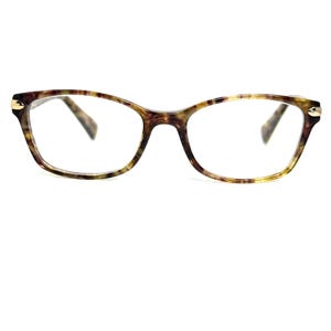 May include: Eyeglasses with a tortoiseshell pattern. The frames have a rectangular shape with rounded edges. The temples are a darker brown color, and the lenses are clear. Small gold accents are on the outer corners of the frames.