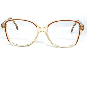 May include: Clear plastic eyeglasses with a brown rim. The glasses have a square shape.