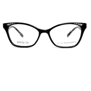 May include: Black cat-eye glasses with a petite fit design. The frames have a decorative pattern at the temples and a tortoiseshell pattern on the arms. The brand name BCBGMAXAZRIA is printed on the right lens.