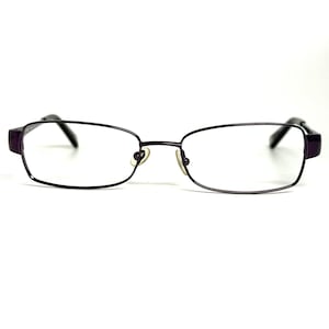 May include: A pair of rectangular eyeglasses with a thin, dark purple metal frame. The glasses feature clear lenses, adjustable nose pads, and dark purple temple arms that extend outward from the sides of the frame, providing a simple design.
