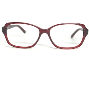 May include: A pair of burgundy-colored eyeglasses with a rounded rectangular frame. The glasses have a dark brown arm and a keyhole bridge. The lenses are clear, and the frame is made of a glossy material.