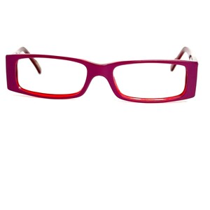 May include: Rectangular eyeglasses with a magenta frame and red inner rims. The temples are a darker red. The glasses are set against a white background.