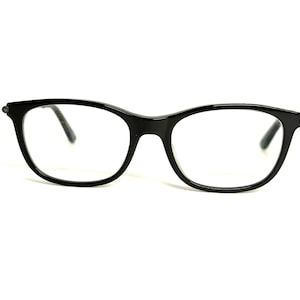 May include: Black eyeglasses with a classic, rounded rectangular frame. The glasses have a glossy finish and clear lenses. The design is simple and elegant, suitable for everyday wear. The frames are approximately 5.5 inches wide.