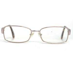 May include: Rectangular eyeglasses with a light pink metal frame and clear lenses. The temples are a darker brown color. The glasses are set against a white background.