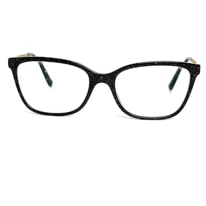 May include: Black cat-eye eyeglasses with a glittery texture on the frames. The glasses have a classic shape with a slight upward curve at the outer edges. The temples have gold-colored accents.