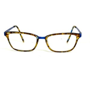 May include: Spectacles featuring a rectangular frame with a brown and tan tortoiseshell pattern on the front rims and temples, accented by a solid blue bridge and blue inner temple tips. The clear lenses are held within the patterned frame.