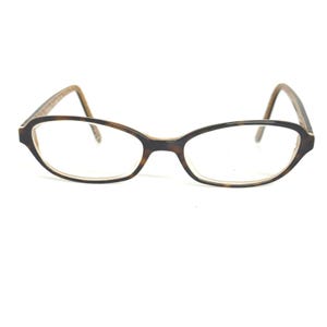 May include: Oval-shaped eyeglasses with a tortoiseshell pattern on the frames. The lenses are clear, and the arms of the glasses are a lighter brown color. The glasses are set against a white background.