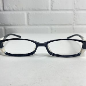 Pode incluir: Óculos retangulares preto e branco com uma armação preta fina e detalhes brancos nas laterais.