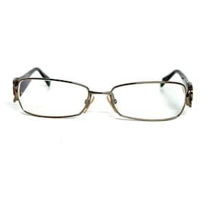 May include: Rectangular eyeglasses with a thin, metallic gunmetal frame. The temples feature a decorative, dark brown patterned accent near the hinges. These glasses include adjustable nose pads and clear lenses, showcasing a sleek, streamlined design.