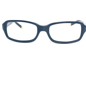 May include: A pair of dark blue rectangular spectacles with a gold accent on the arms.