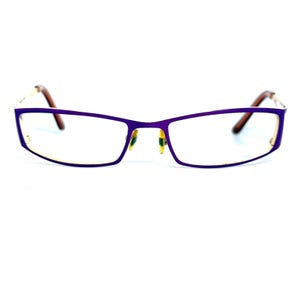 May include: Rectangular eyeglasses featuring a vibrant purple metal frame. The glasses have clear lenses, adjustable nose pads, and thin temples with brown tips. The design is sleek and streamlined, showcasing a bold purple color throughout the front.