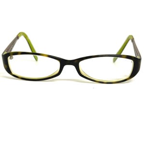May include: Eyeglasses with a dark brown and green tortoiseshell pattern frame and green temples. The rectangular lenses are surrounded by a light yellow border. The glasses are set against a white background.