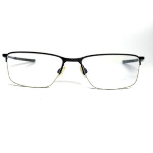May include: Rectangular eyeglasses featuring a thin black metal frame across the top and clear lenses. The design includes adjustable nose pads and slender temples, providing a clean and functional look for everyday vision correction needs.