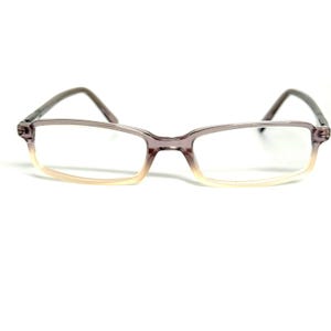 May include: Rectangular eyeglasses featuring a translucent frame that transitions from a deep purple hue at the top to a clear, pale beige tone at the bottom. The glasses have thin, matching purple temples and a standard bridge connecting the lenses.