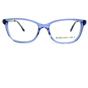 May include: A pair of light blue eyeglasses with a cat-eye frame. The glasses have clear lenses and dark gray temples. The brand name "BCBGMAXAZRIA" is printed on the right lens.