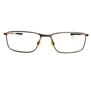 May include: Rectangular eyeglasses with a dark metallic bronze frame. The glasses feature clear lenses, a thin bridge, and adjustable nose pads. The temple arms are visible on the sides, showing a hint of red and blue detailing at the hinges.