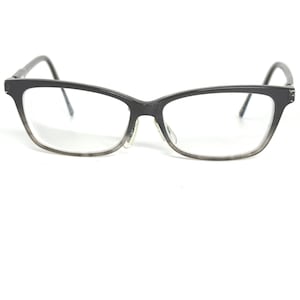 May include: Black eyeglasses with a gradient gray lower frame and clear lenses. The glasses have a rectangular shape with a slight cat-eye design. The temples are thin and dark.