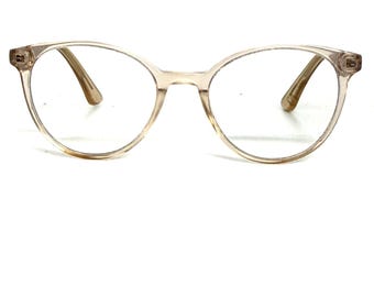 May include: Clear, round-framed eyeglasses with a light brown tint. The frames have a subtle, translucent appearance, and the temples are a darker shade of brown. The glasses are designed for vision correction.