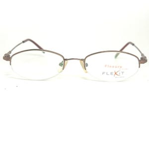 May include: Oval-shaped eyeglasses with a brown metal frame. The lenses are clear, and the lower portion of the lenses are rimless. The temples and nose bridge are also brown. The text "Flexure" and "FLEXIT" are printed on the right lens.