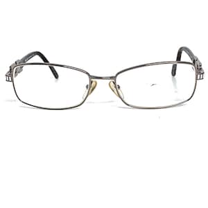 May include: A pair of silver-toned metal spectacles with rectangular frames and clear lenses.