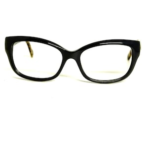 May include: Black eyeglasses with a thick, rounded frame shape. The front of the frames is solid black, while the inner side of the temple arms features a brown and black tortoiseshell pattern. The lenses are clear and the bridge is curved.