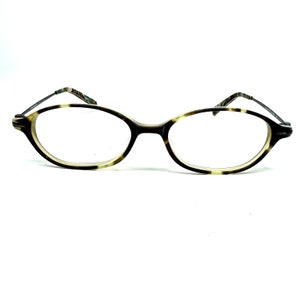 May include: A pair of oval-shaped eyeglasses with a tortoise shell frame. The frame is brown with a light brown pattern.