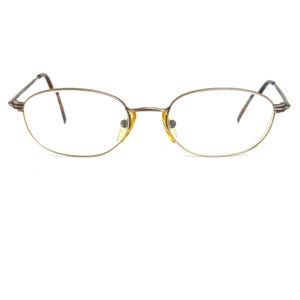 May include: A pair of gold-toned oval-shaped eyeglasses with clear lenses.